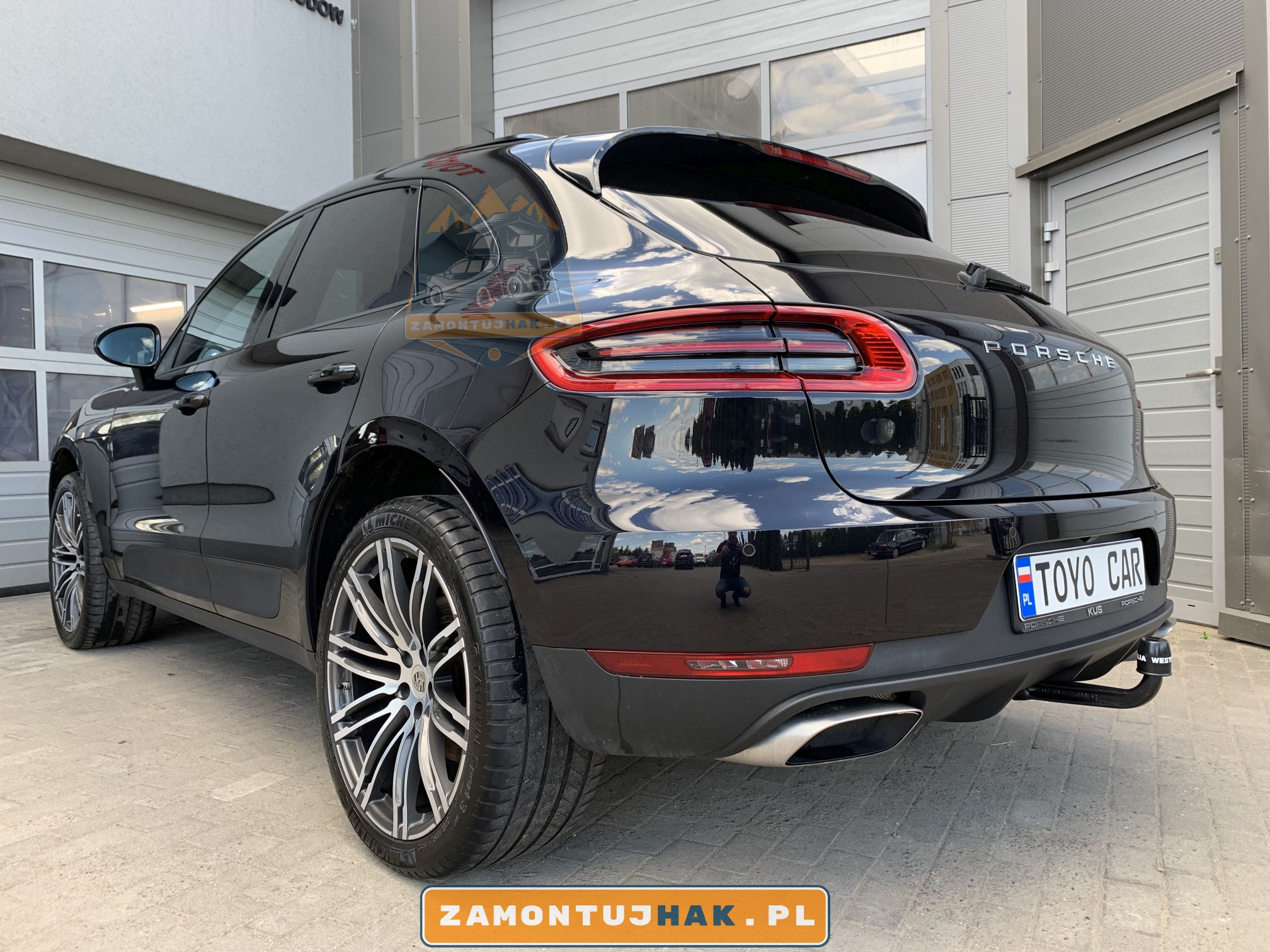 na zdjęciu samoch&oacute;d osobowy Porsche Macan z hakiem holowniczym za tylnym zderzakiem hak westfalia 327068600001 model a40v dobrze widoczny na zdjeciu z lewego tylnego rogu samochodu widac jak wygląda samoch&oacute;d z hakiem holowniczym 